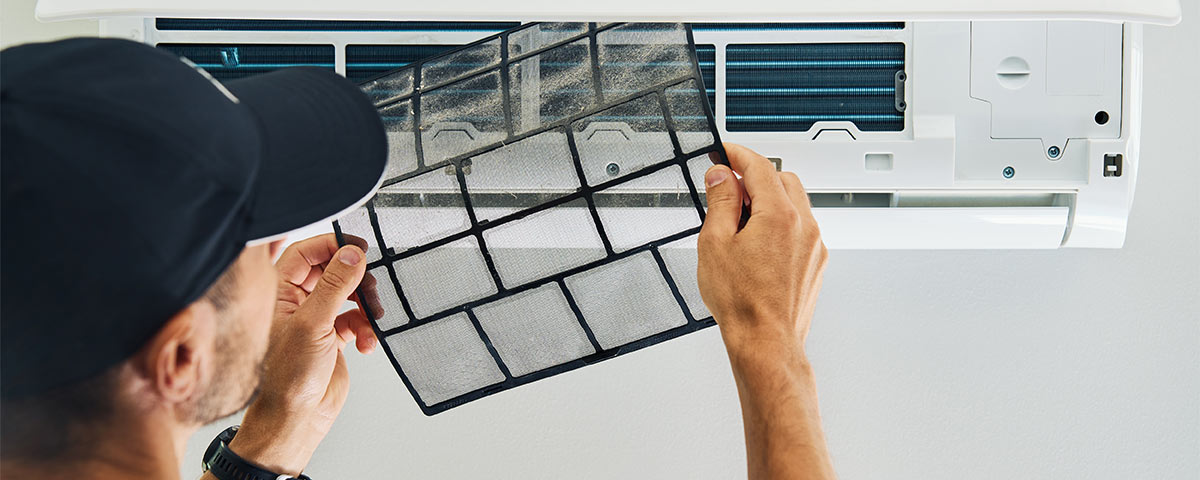 man changing air filter on ductless air conditioner